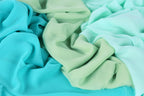 a close-up view of a pile of fabric with a mix of turquoise and mint green colors. The fabric appears to be crumpled and wrinkled, giving it a textured and soft appearance.