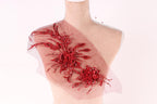 A mannequin wearing a red floral embellishment on its shoulder.