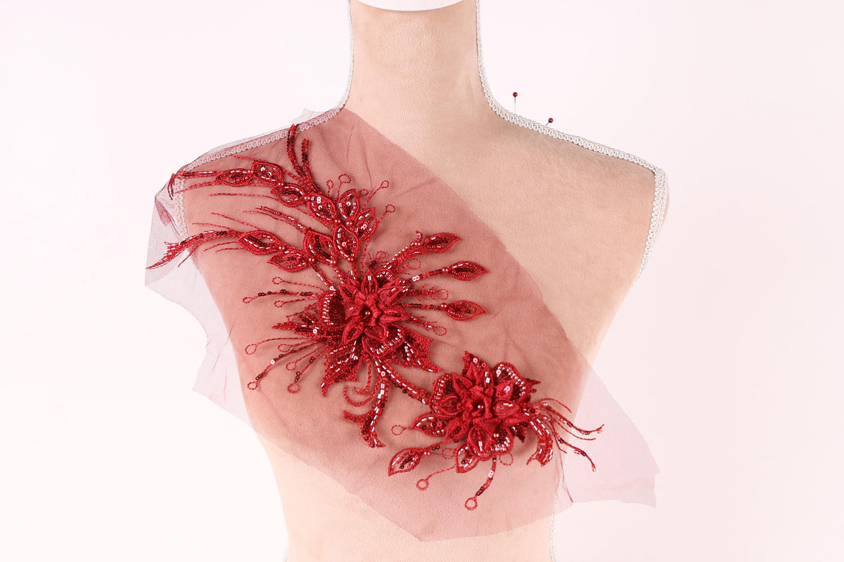 A mannequin wearing a red floral embellishment on its shoulder.