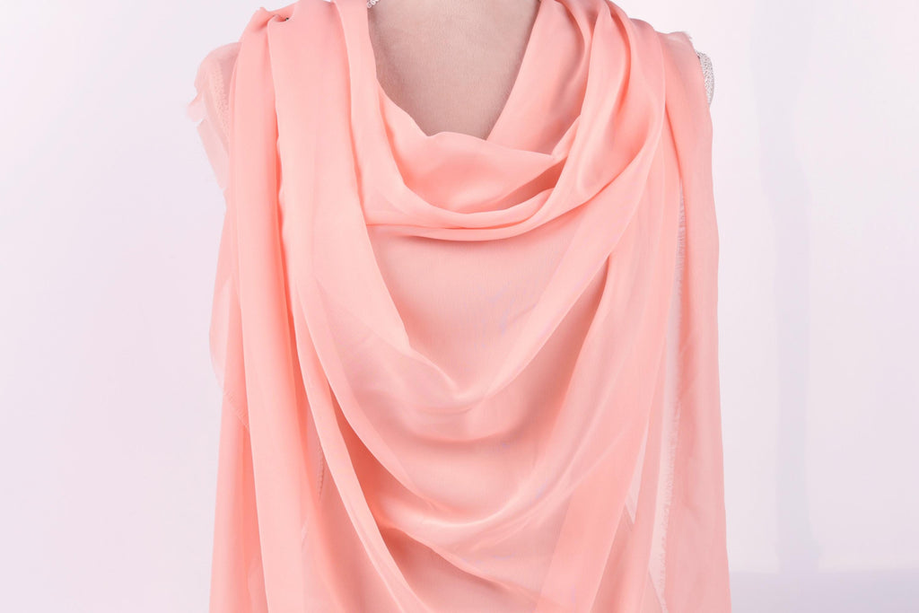 A pink scarf draped over a mannequin, creating a soft and flowing appearance.