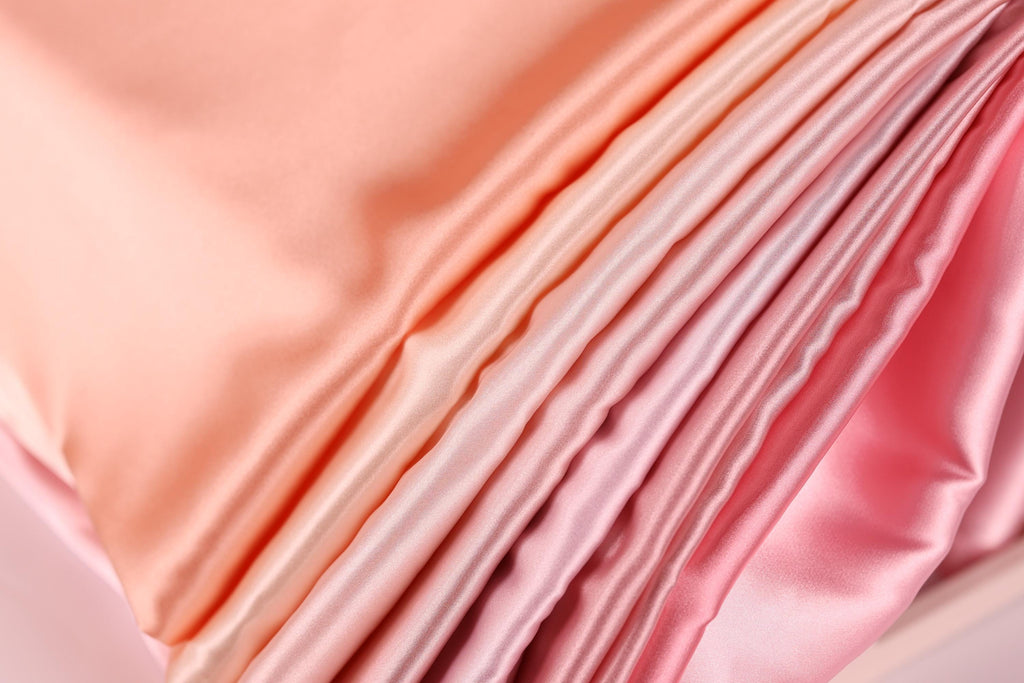A close-up view of a soft, flowing fabric with a gradient of pink and peach colors, creating a visually appealing and textured appearance.