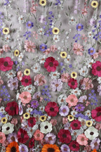a vibrant and colorful floral pattern, with a variety of flowers in shades of pink, purple, yellow, and orange. The flowers are intricately embroidered or sewn onto a fabric, creating a visually striking and detailed design.