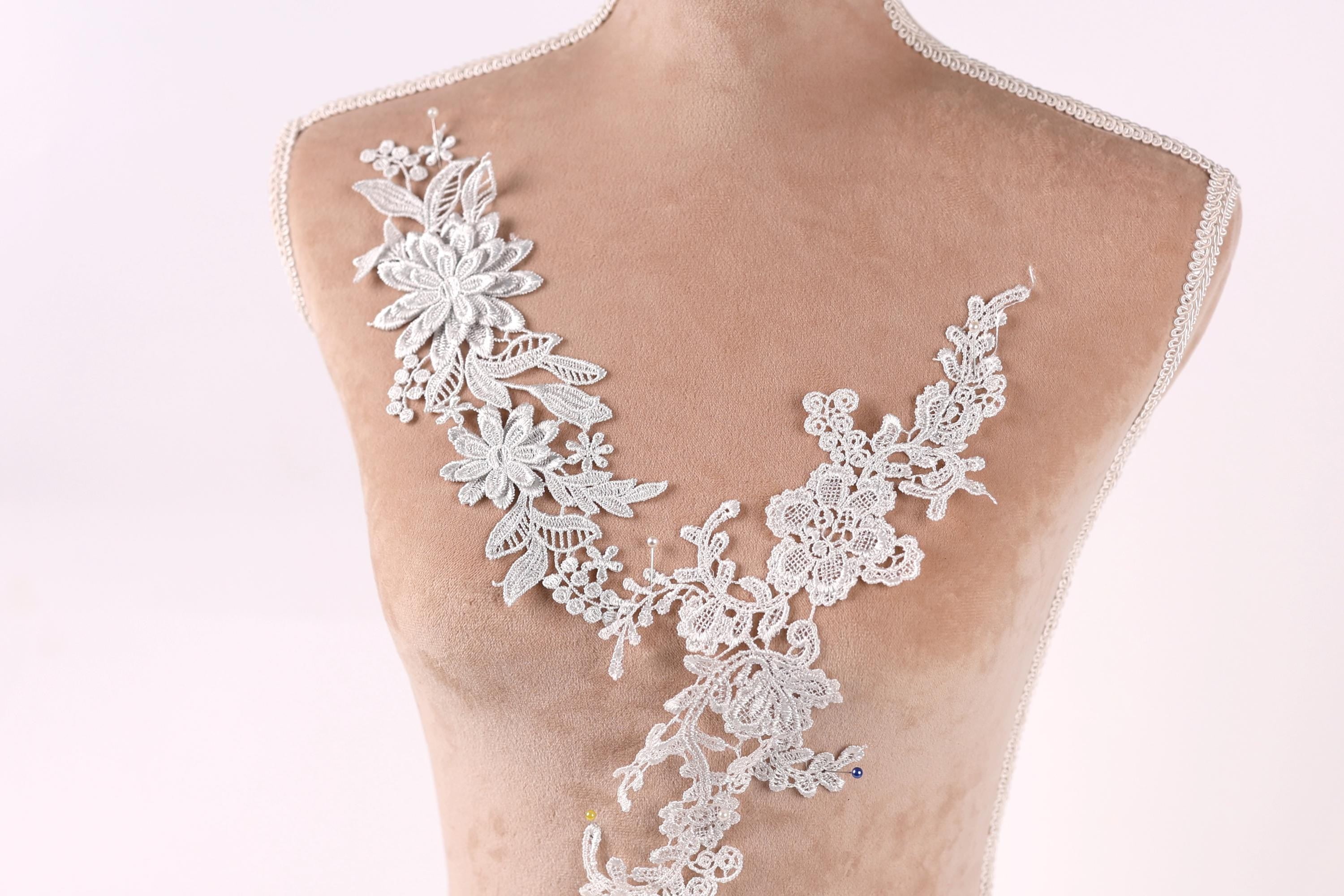 A mannequin torso with a delicate, intricate lace design on the bust area, featuring a floral pattern.