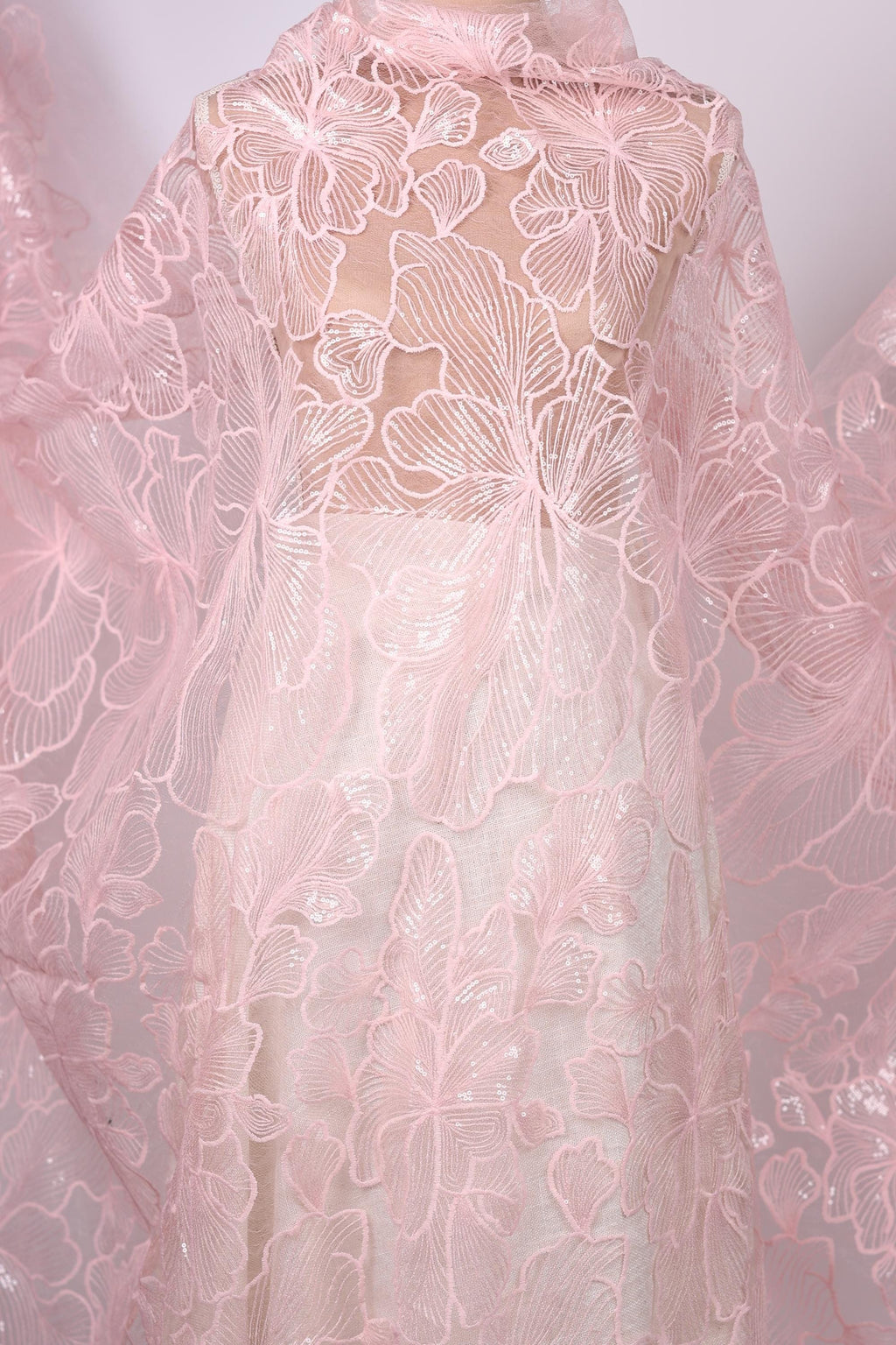 a close-up view of a delicate, pink lace fabric with intricate floral patterns.