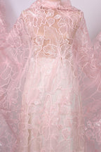 a close-up view of a delicate, pink lace fabric with intricate floral patterns.