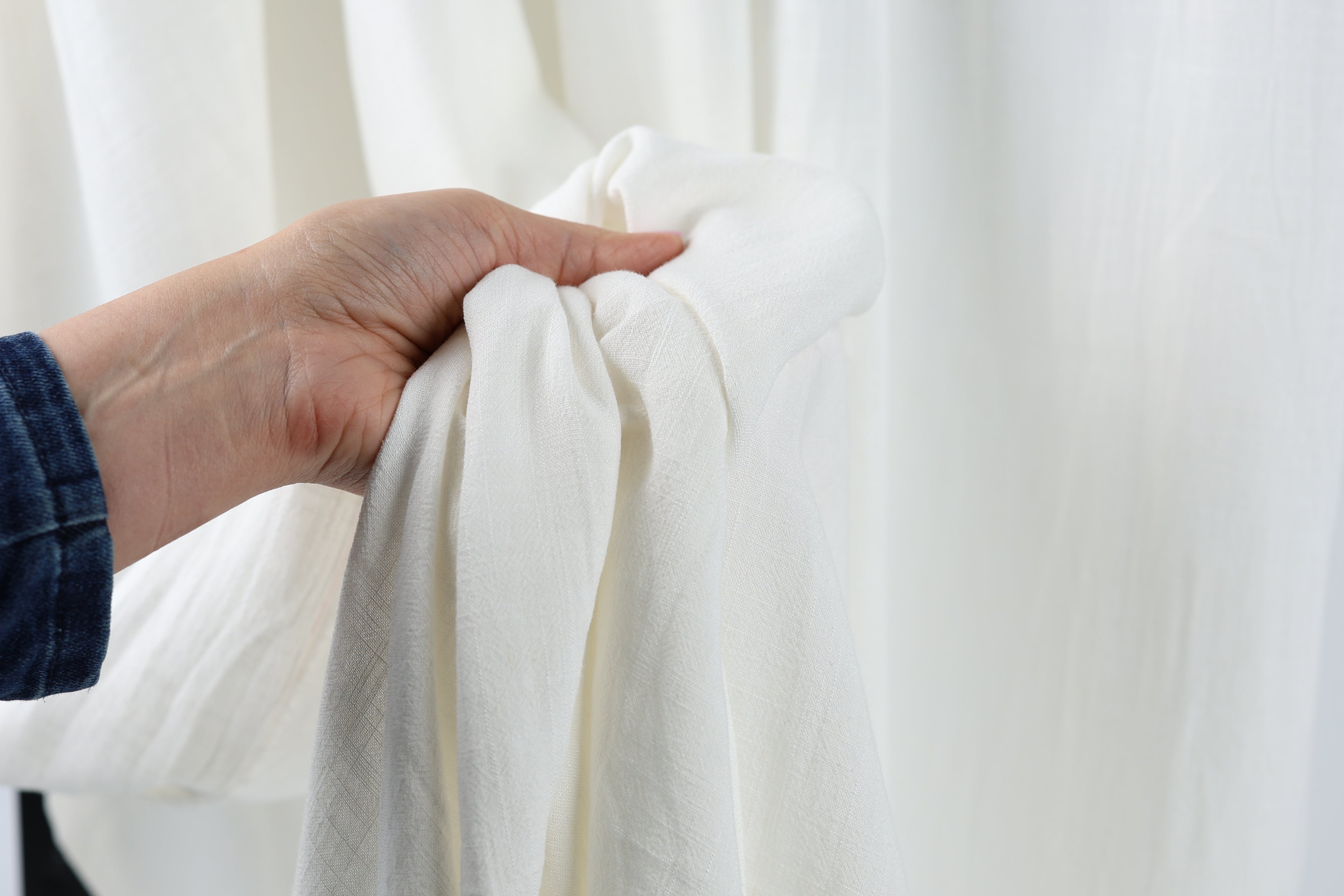 A hand holding a white cloth against a white background.