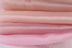 A close-up image of a stack of soft, light pink fabric, with a focus on the texture and color of the fabric.