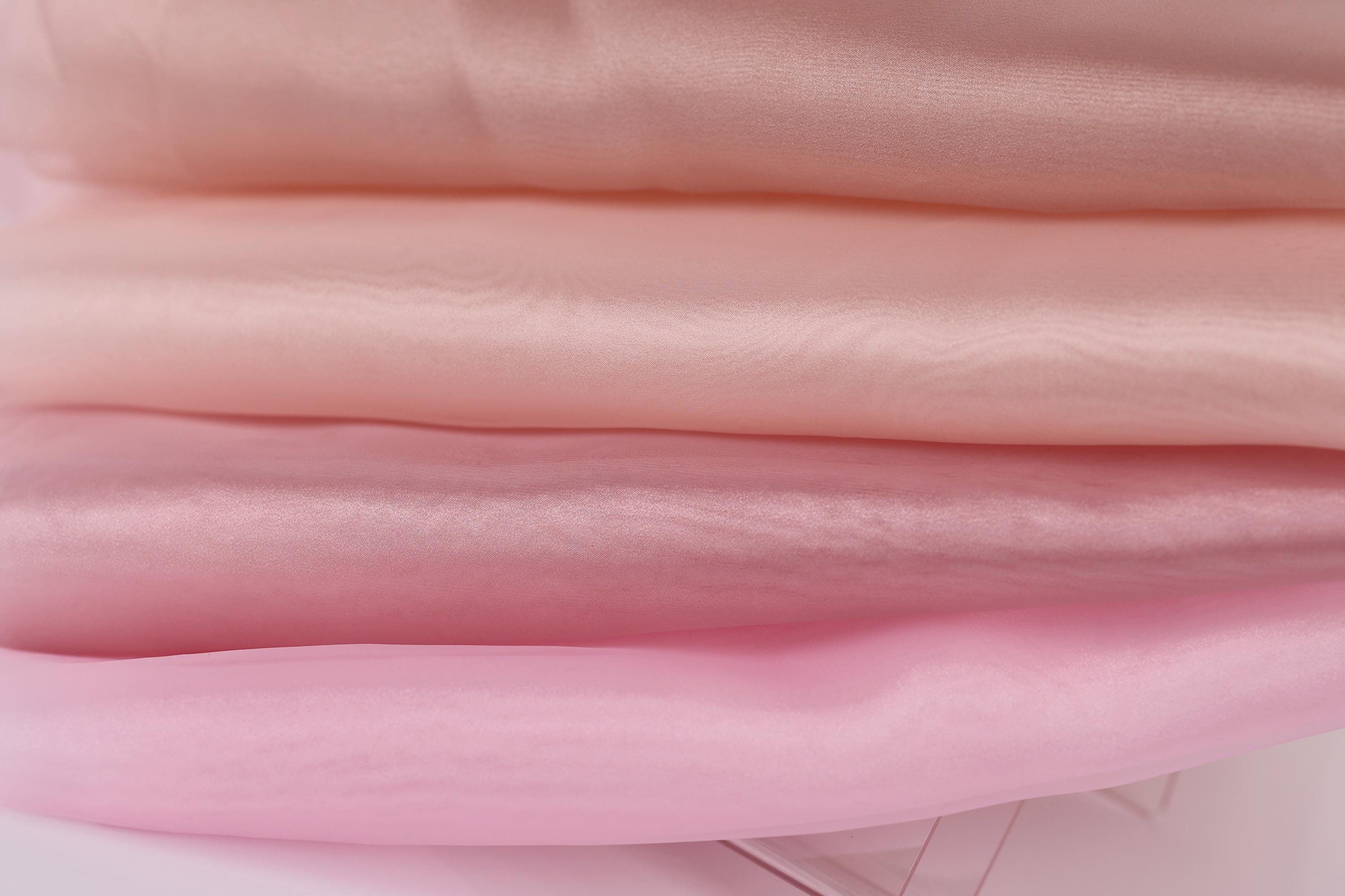 A close-up image of a stack of soft, light pink fabric, with a focus on the texture and color of the fabric.