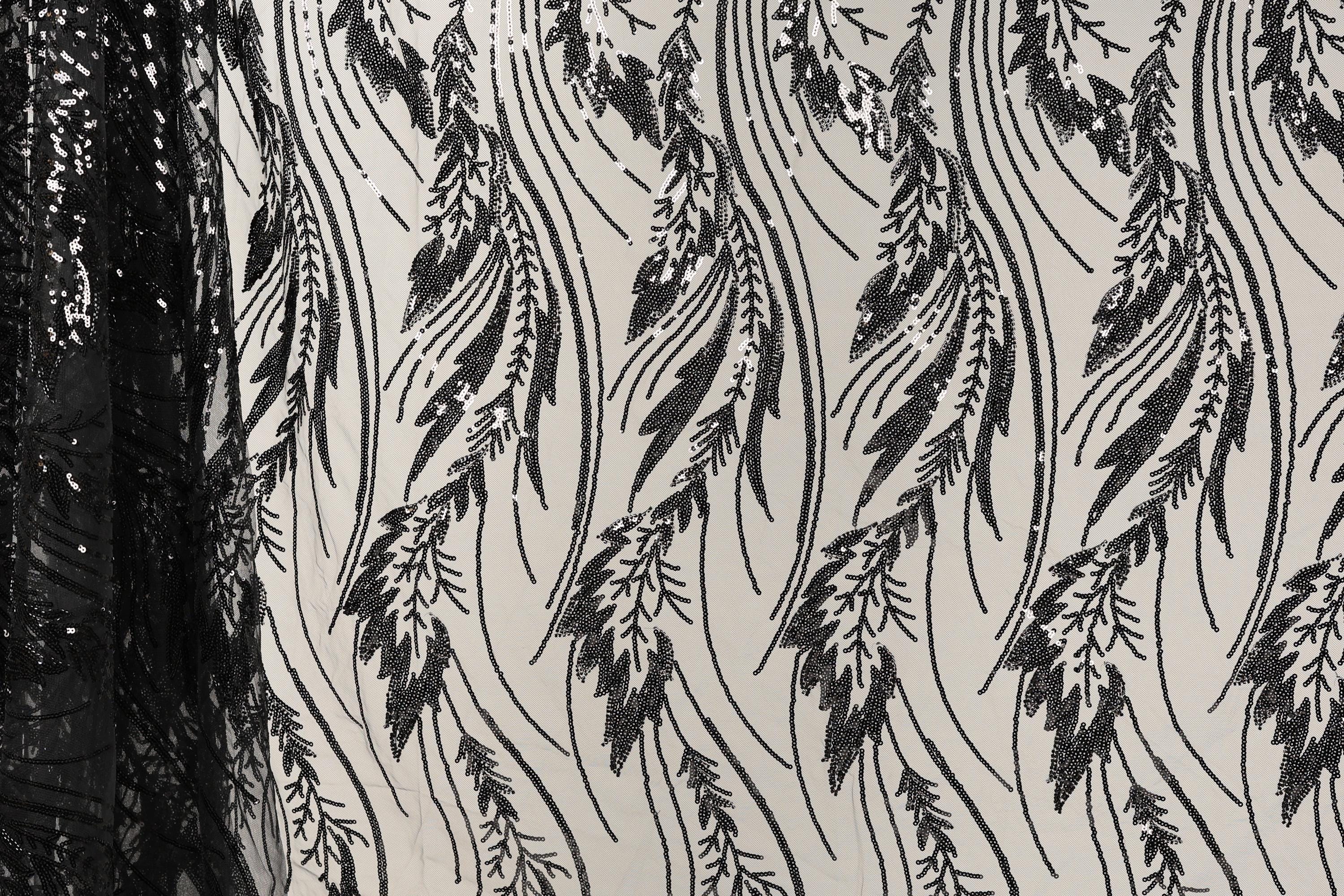 a close-up view of a fabric with a repeating pattern of black and white leaf-like designs. The pattern is intricate and detailed, with the leaves appearing to be made of sequins or beads. The fabric appears to be a sheer material, allowing the leaves to be visible through the sheerness. The image does not contain any text or other discernible objects or actions.