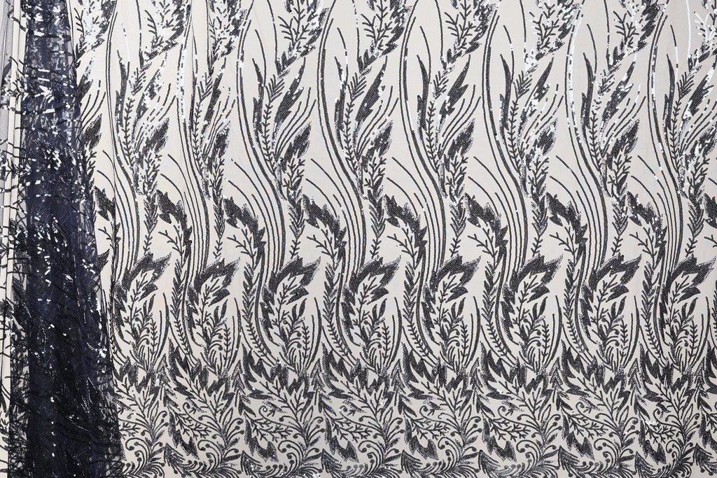 a close-up view of a fabric with a repeating pattern of black and white floral designs. The pattern consists of numerous small leaves and flowers arranged in a repeating diagonal line across the fabric. The fabric appears to be made of a material with a textured surface, which adds depth and visual interest to the overall design.