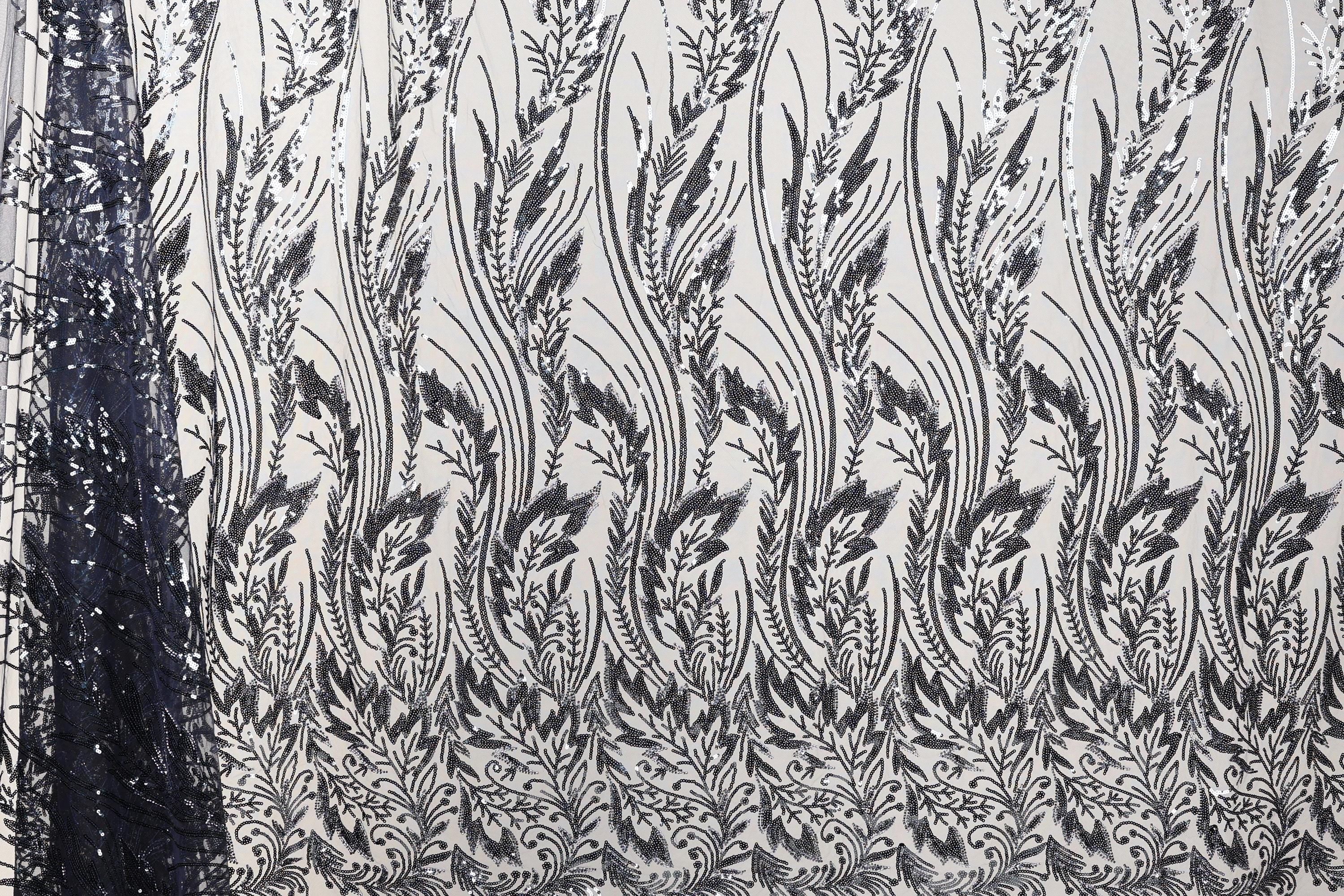 a close-up view of a fabric with a repeating pattern of black and white floral designs. The pattern consists of numerous small leaves and flowers arranged in a repeating diagonal line across the fabric. The fabric appears to be made of a material with a textured surface, which adds depth and visual interest to the overall design.