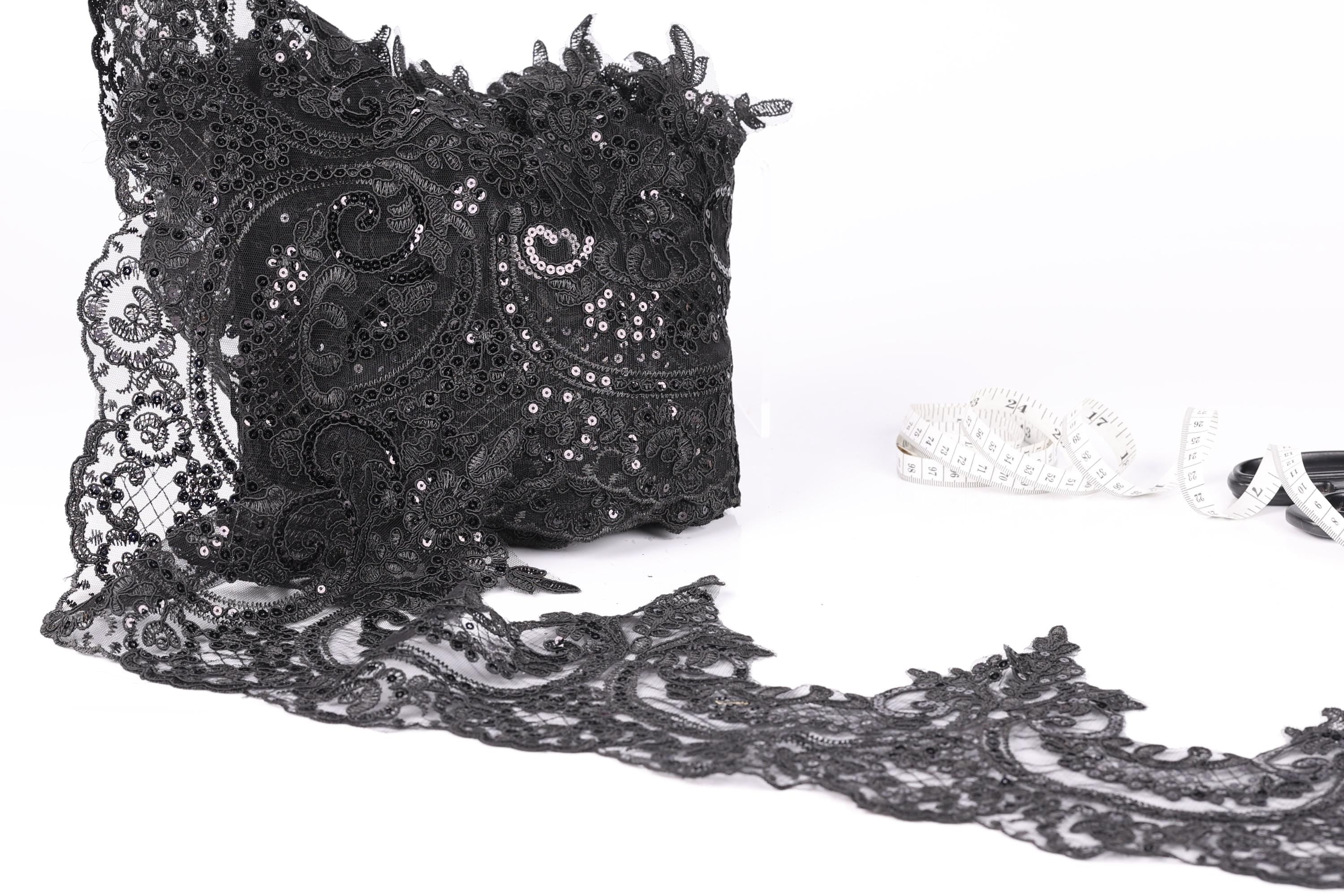 a close-up view of a black lace fabric with intricate patterns and designs, including a lace trim.