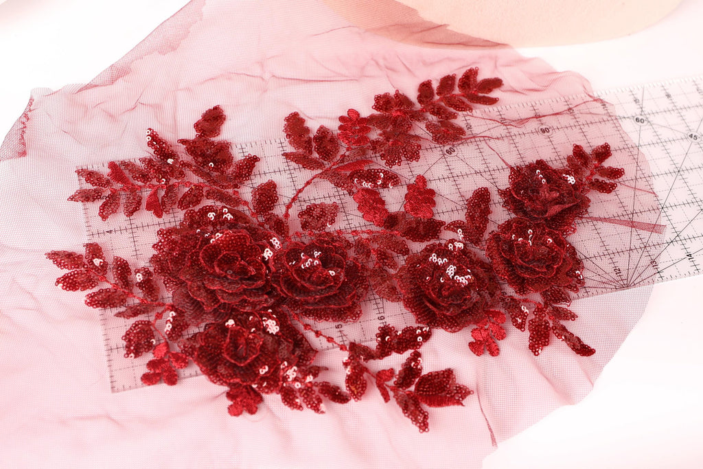 a close-up view of a red sequin flower design on a pink background.