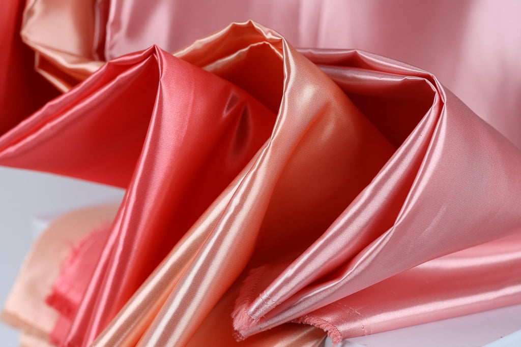 a close-up view of a fabric with a pink and orange color scheme, featuring a soft and flowing texture.
