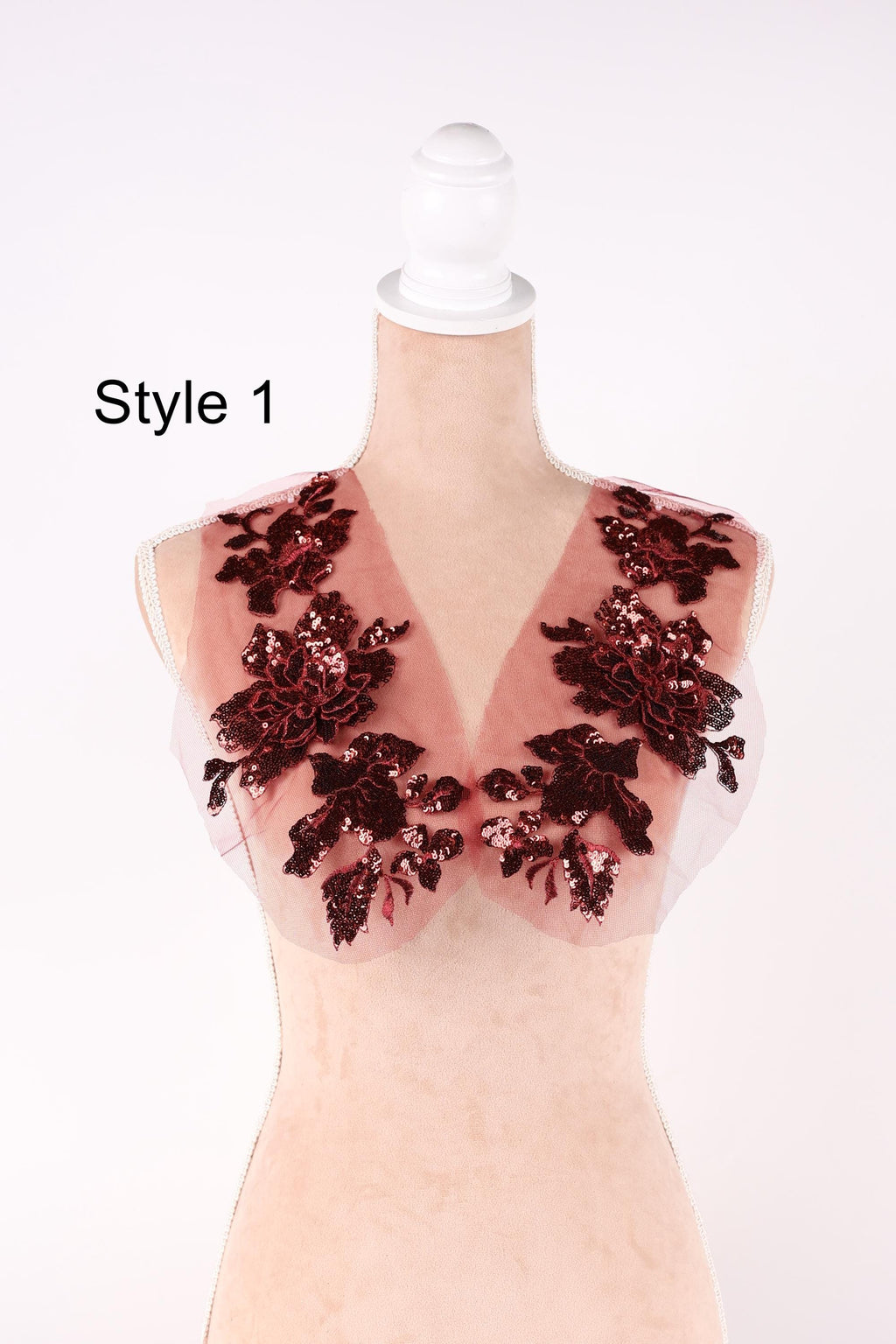 A mannequin wearing a red and black floral-patterned vest with sequin details.