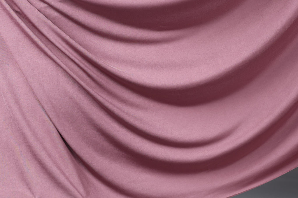 a close-up view of a soft, flowing pink fabric, possibly silk or satin, with a smooth, shiny texture.