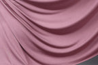 a close-up view of a soft, flowing pink fabric, possibly silk or satin, with a smooth, shiny texture.