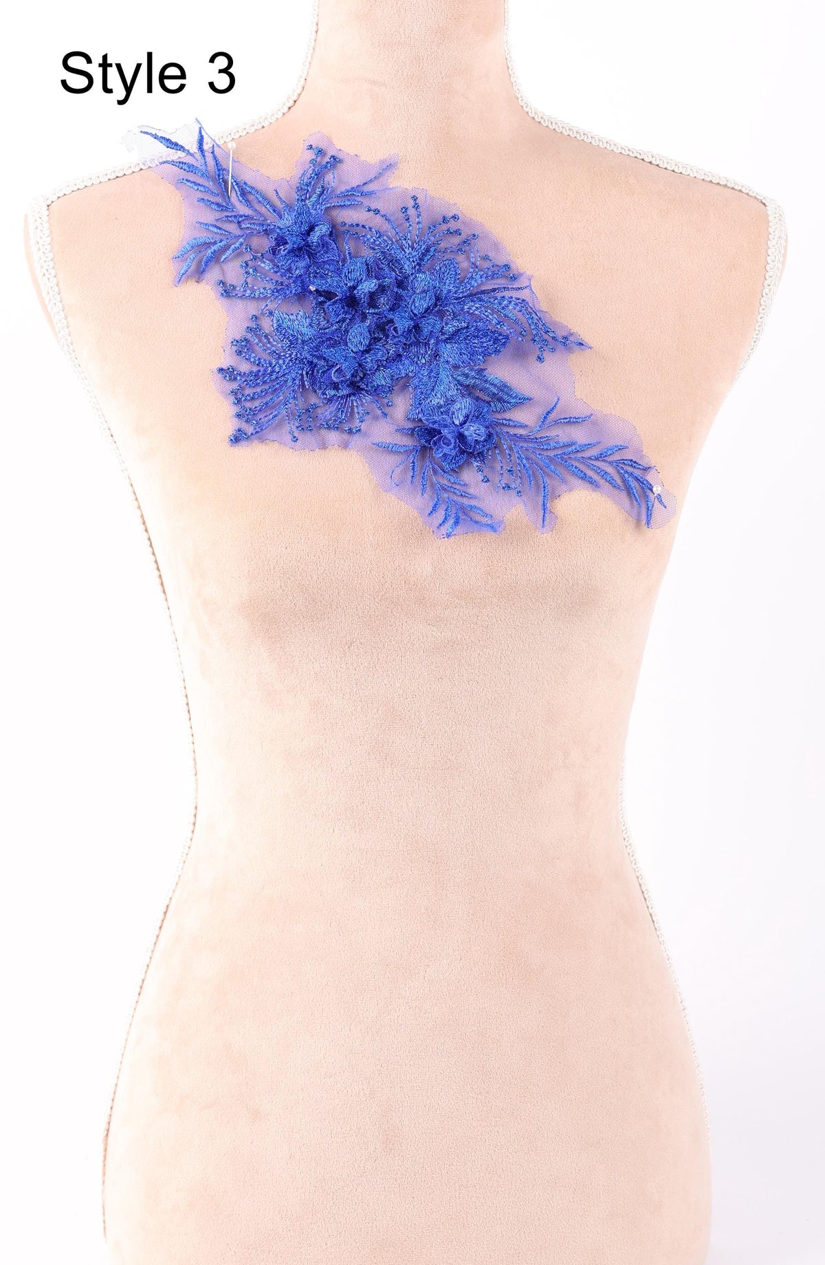 A mannequin with a decorative blue floral piece on its shoulder.