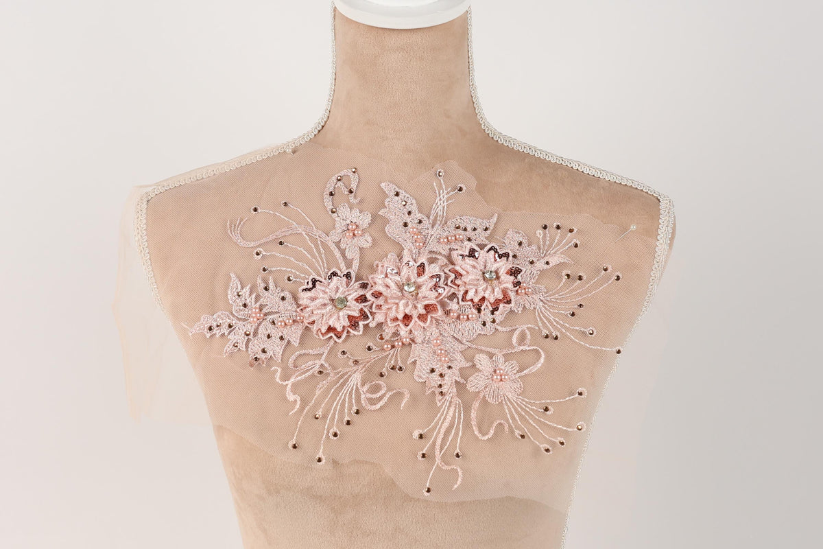 A mannequin with a delicate, floral-patterned fabric draped over its torso.