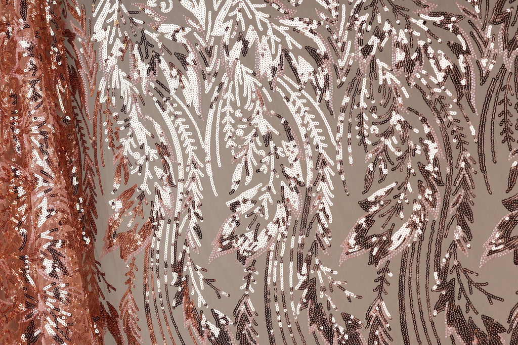 a close-up view of a fabric with a repeating pattern of pink and brown sequin designs. The pattern appears to be a floral or leaf-like design, with the sequins arranged in a way that creates a sense of movement and texture. The fabric is predominantly pink and brown, with the pink sequins standing out against the brown background. The image does not contain any text or other discernible objects, and the focus is solely on the intricate and visually appealing pattern of the sequin fabric.