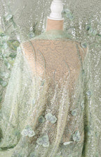 a mannequin wearing a sheer, mint green fabric with a floral pattern. The fabric appears to be made of sheer lace or sheer mesh, with a delicate, embroidered design. The mannequin is positioned in front of a background that is also covered in a similar mint green fabric with a floral pattern, creating a cohesive and visually appealing display.