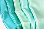 A close-up image of a fabric with a gradient of turquoise to mint colors, creating a visually appealing and vibrant pattern.