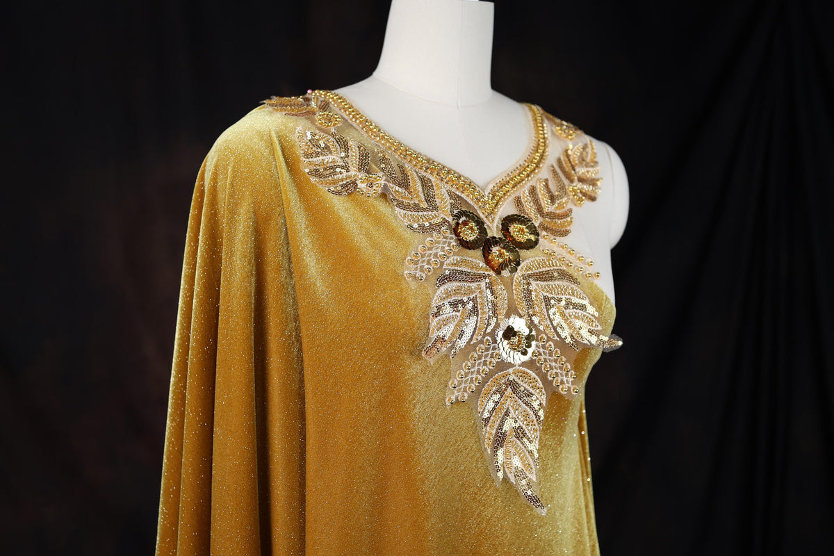 A gold dress with a draped, flowing silhouette and intricate beading and embroidery details.