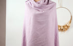 A person is standing in front of a white wall, wearing a purple scarf.