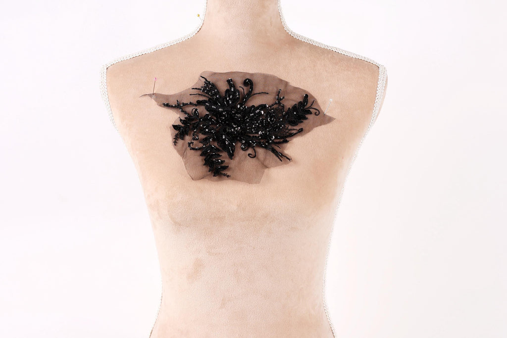 a mannequin torso with a black floral embroidered on it.