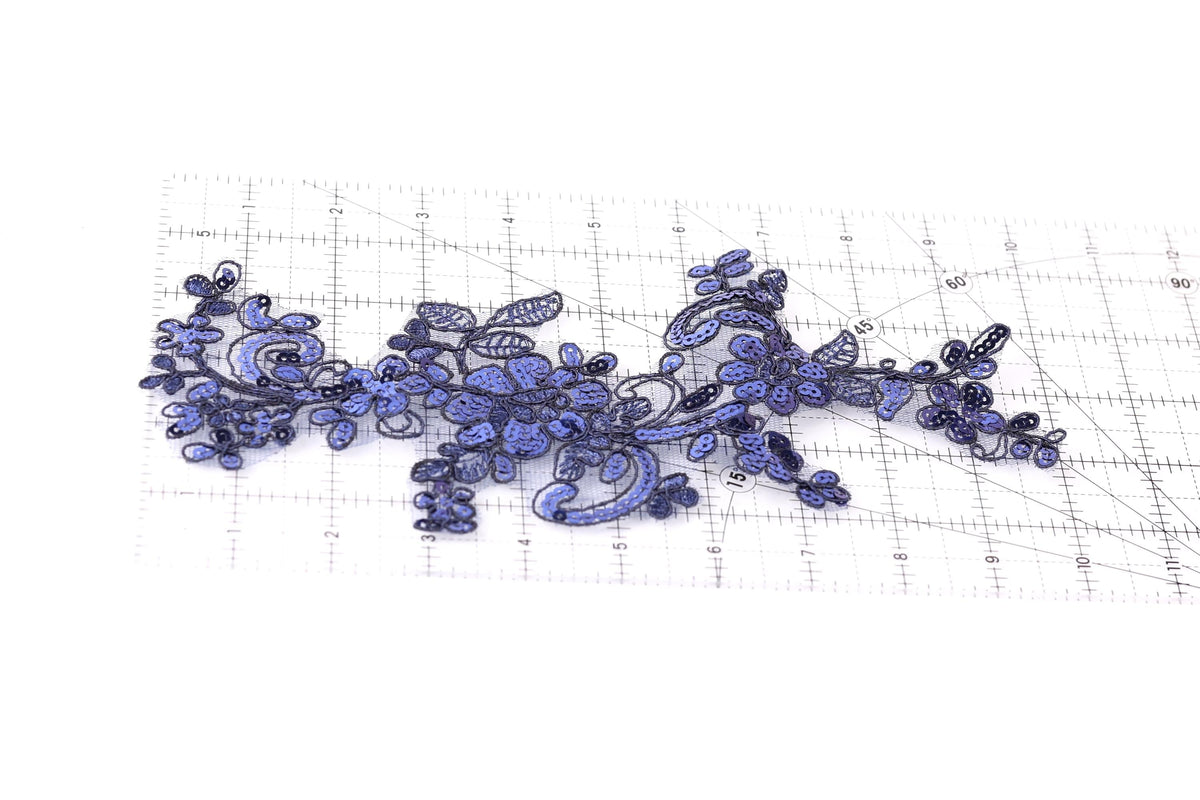 a close-up view of a piece of fabric with a floral pattern, including blue and purple flowers, and a ruler for scale.