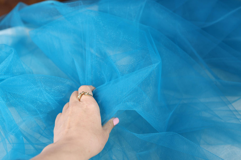 a woman's hand touching a blue tulle