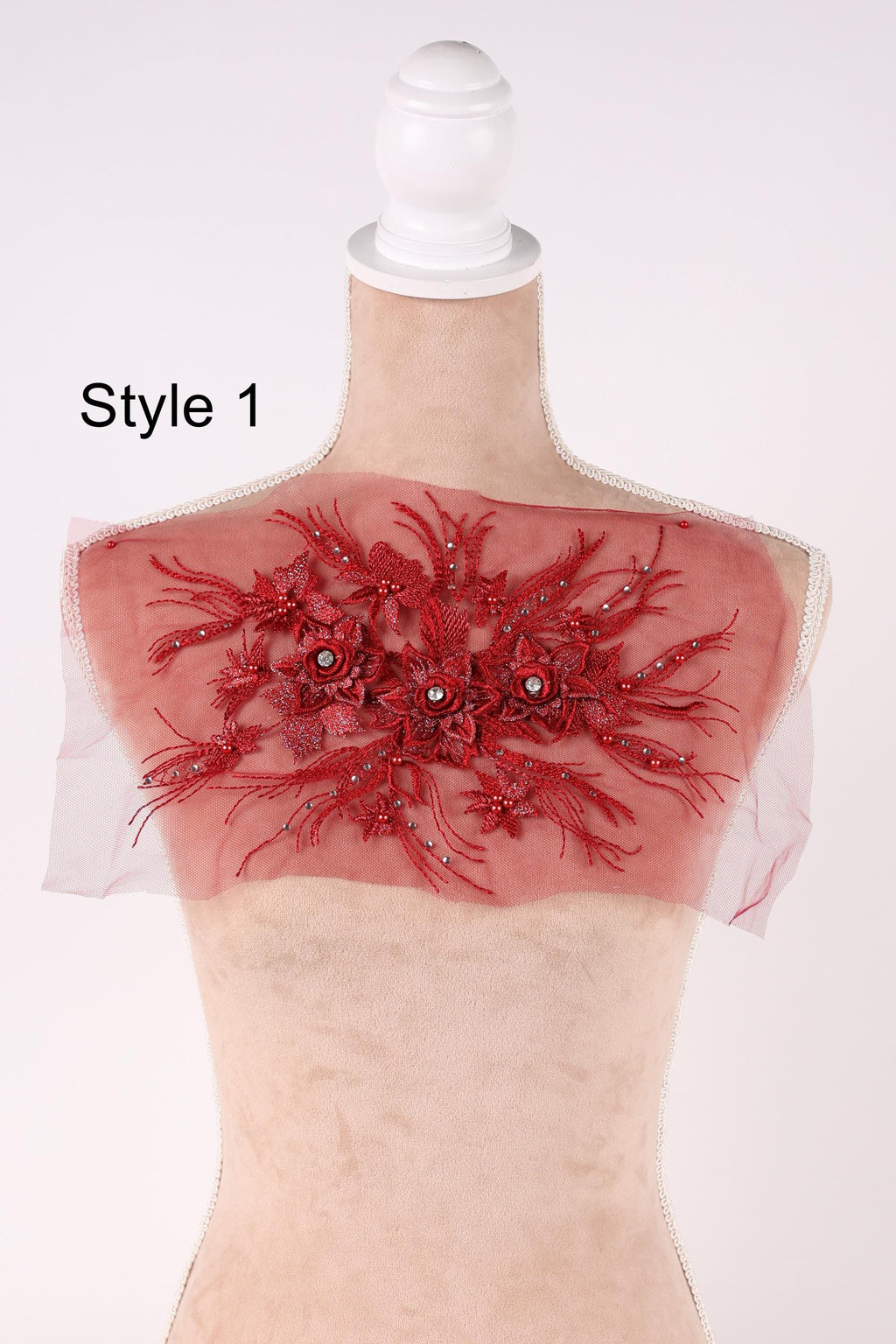 A mannequin with a red floral embellishment on its shoulder, displayed against a white background.