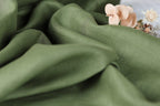 a close-up view of a green fabric with a delicate flower resting on it.