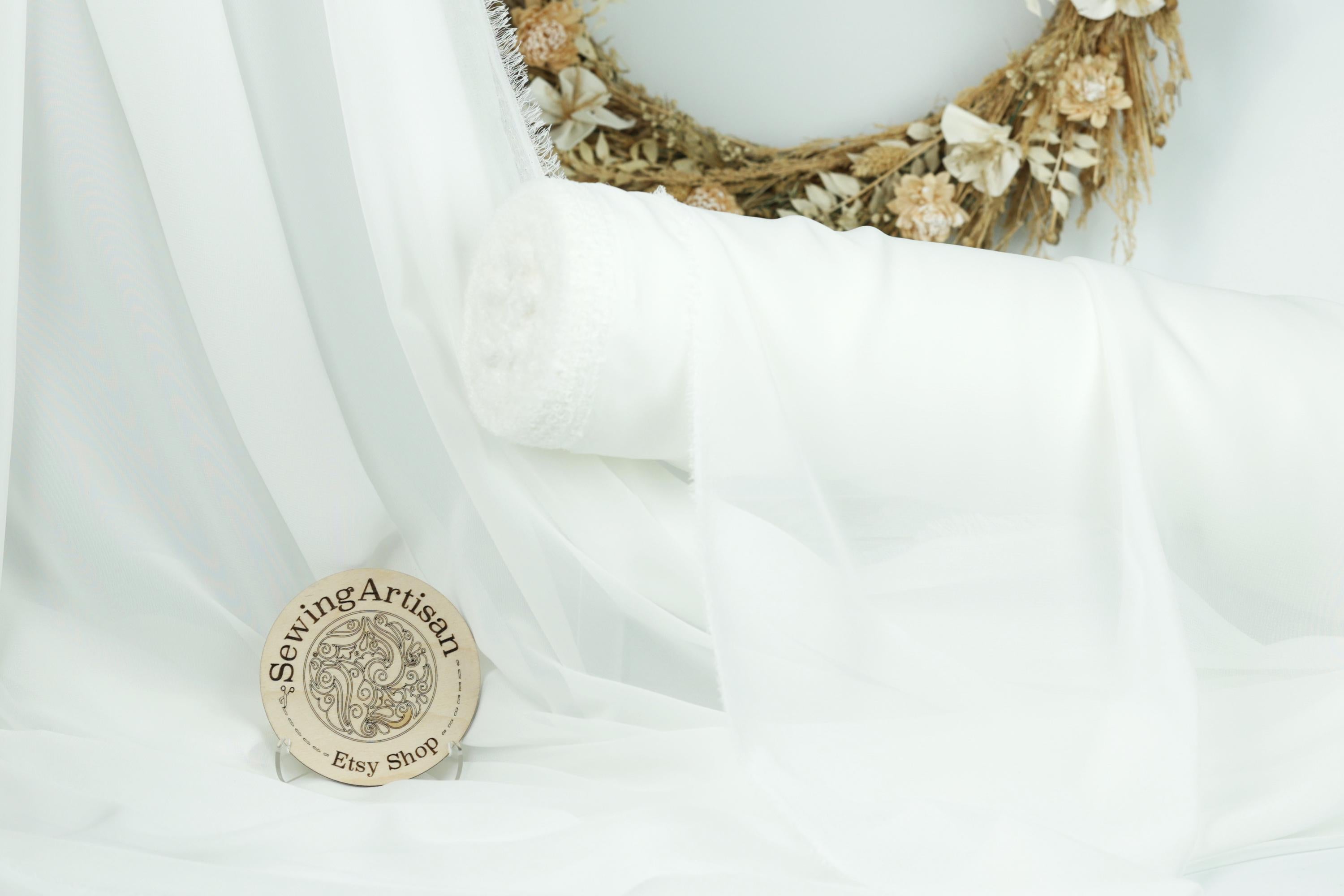 a sewing artisan&#39;s shop, with a white fabric roll, a wreath, and a circular sign with text.