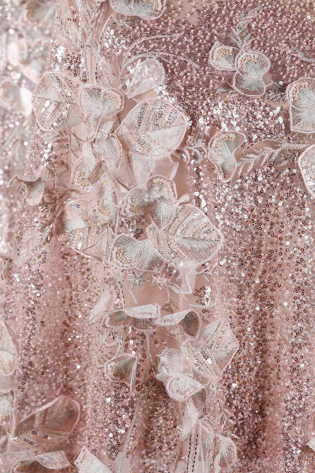 The image is a close-up of a delicate, pink sequined dress with intricate floral embroidery.
