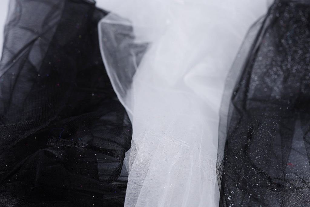 a close-up view of a black and white fabric, with the black fabric appearing more prominent in the foreground and the white fabric slightly blurred in the background.