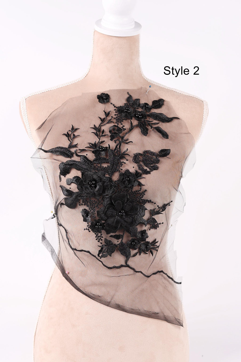A mannequin wearing a black lace dress with a floral pattern on the front.