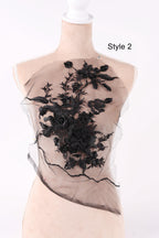 A mannequin wearing a black lace dress with a floral pattern on the front.