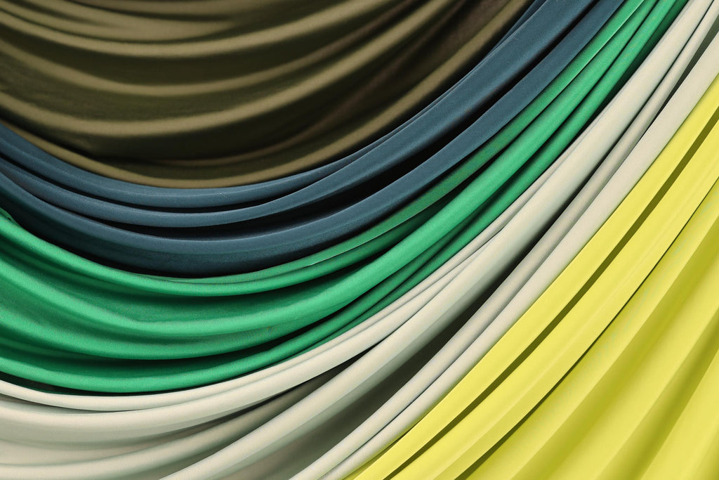 a close-up view of a variety of colorful fabrics, including green, blue, yellow, and white, arranged in a visually appealing manner.