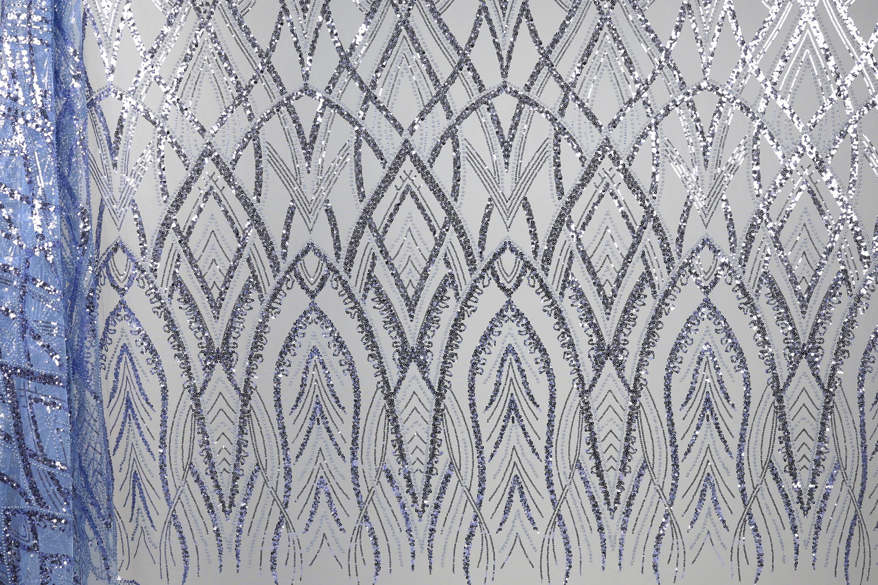 a close-up view of a fabric with a repeating pattern of silver and blue sequin designs. The pattern consists of a series of arched shapes and lines that create a visually striking and intricate design. The fabric appears to be a type of sheer material, with the silver and blue sequins adding a touch of sparkle and elegance to the overall appearance.