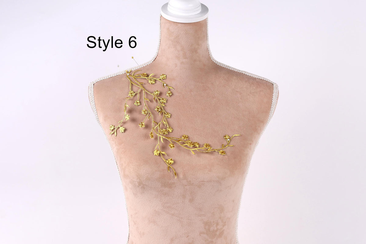 A mannequin with a gold floral design on its shoulder, against a white background.