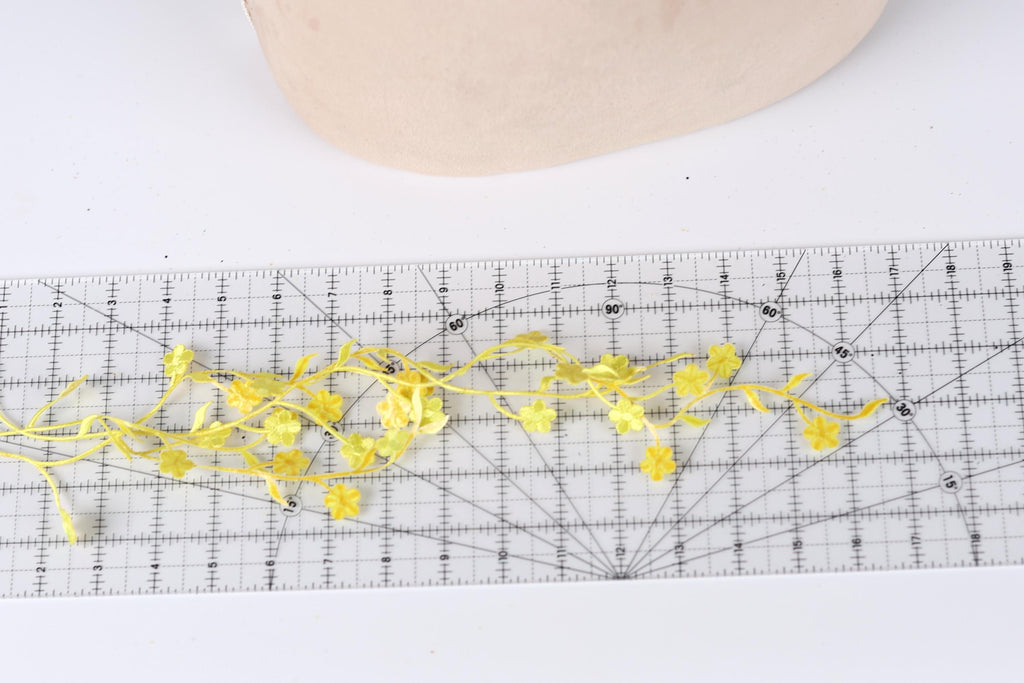a clear ruler with yellow flower-shaped cutouts placed on it, creating a decorative arrangement.