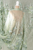 a mannequin wearing a dress with a sheer, green and white floral pattern. The dress appears to be made of a sheer fabric with a floral design, giving it a delicate and elegant appearance.