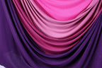 a close-up view of a fabric with a gradient of colors, transitioning from purple to pink and then to a darker shade of pink. The fabric appears to be made of a shiny, glittery material, adding a touch of sparkle to the overall appearance.