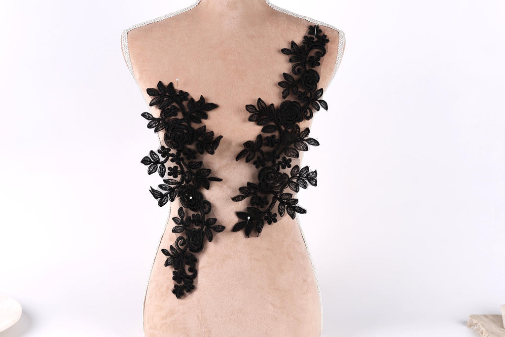 A mannequin torso with black floral lace appliques on it.