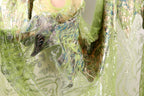 a close-up view of a fabric with a green and silver pattern, including a floral design and metallic elements.