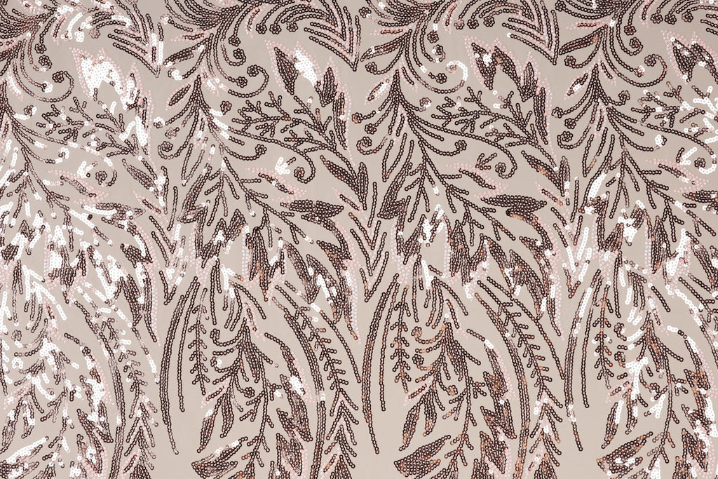 a close-up view of a fabric with a repeating pattern of brown and white sequin designs. The pattern appears to be a floral or leaf-like design, with the sequins arranged in a way that creates a sense of movement and texture. The fabric has a light brown or beige background, which contrasts with the dark brown and white colors of the sequins. The image does not contain any text or other discernible objects, and the focus is solely on the intricate and detailed pattern of the sequin design.