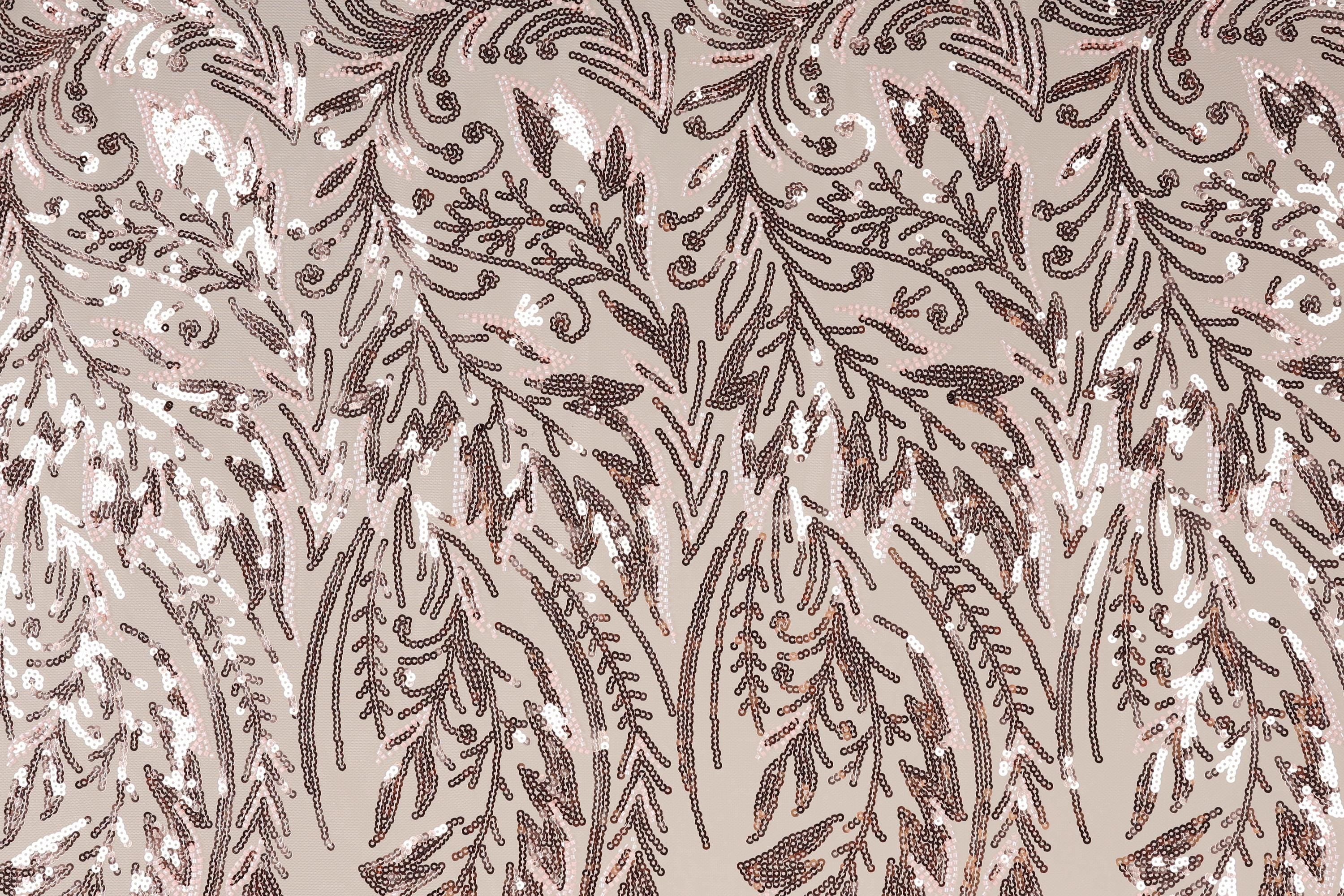 a close-up view of a fabric with a repeating pattern of brown and white sequin designs. The pattern appears to be a floral or leaf-like design, with the sequins arranged in a way that creates a sense of movement and texture. The fabric has a light brown or beige background, which contrasts with the dark brown and white colors of the sequins. The image does not contain any text or other discernible objects, and the focus is solely on the intricate and detailed pattern of the sequin design.