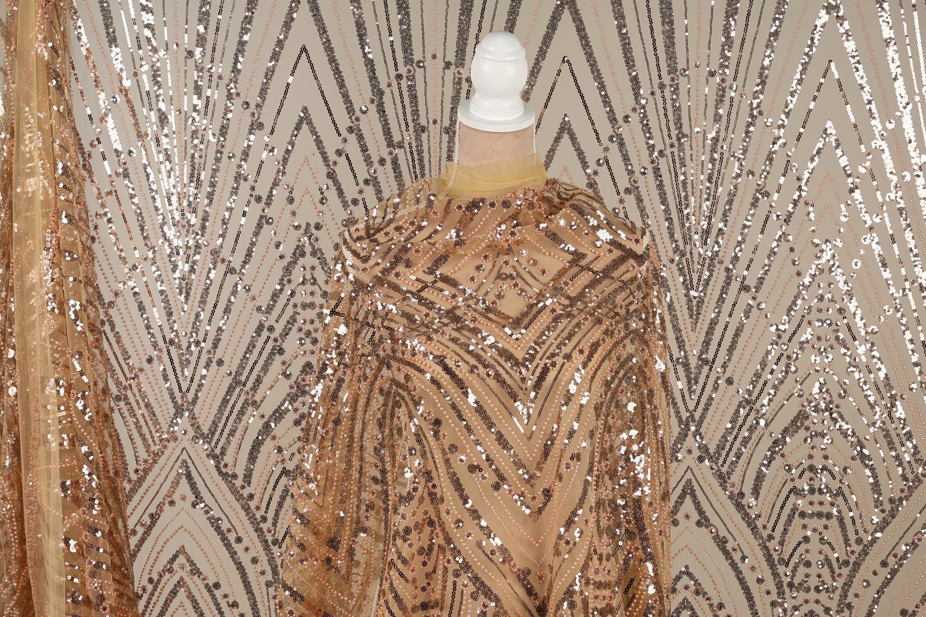 a mannequin wearing a gold sequin dress with a geometric pattern.