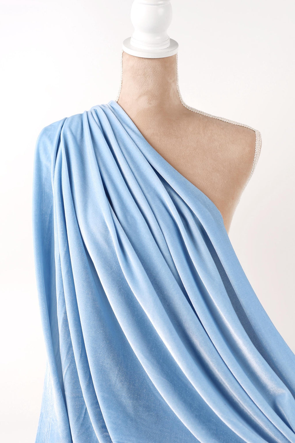 A mannequin wearing a blue draped fabric draped over its body.